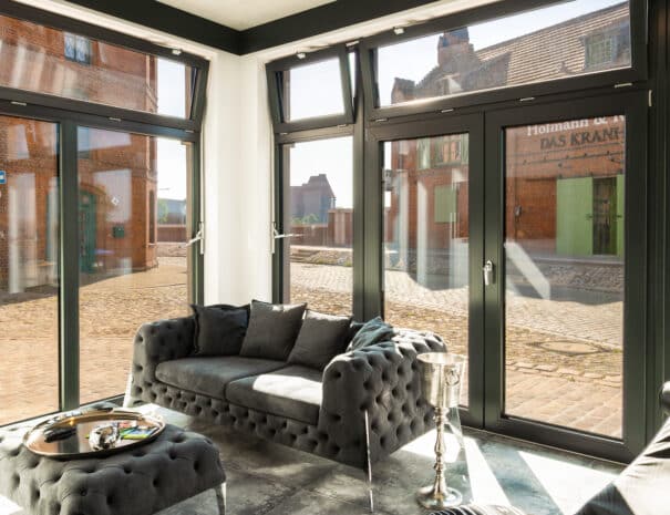 Helles Wohnzimmer mit großem Sofa und Panoramafenstern im ELBE.6 Apartment I in Wittenberge.