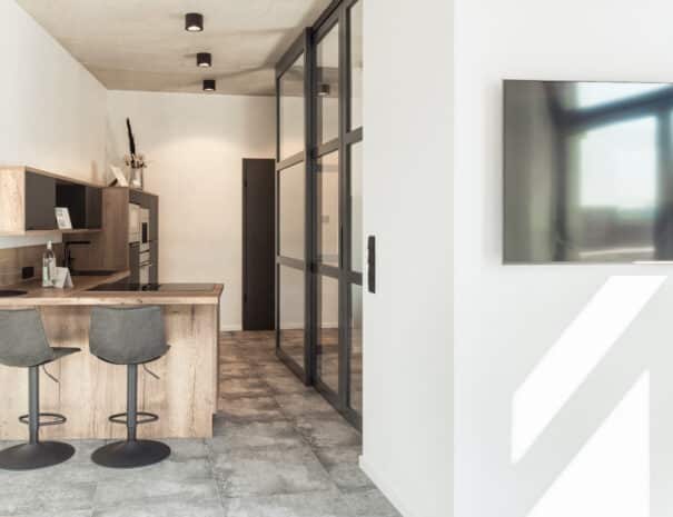 Helle, offene Wohnküche mit Tresen und zwei Barhockern im ELBE.6 Apartment I in Wittenberge.