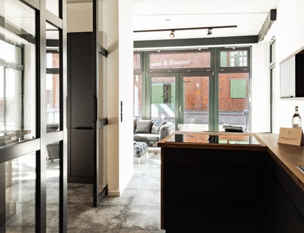 Modernes Ferienapartment im Loft-Stil bei ELBE.6-Apartments in Wittenberge mit offener Küche, Glaswänden und gemütlicher Sitzecke.