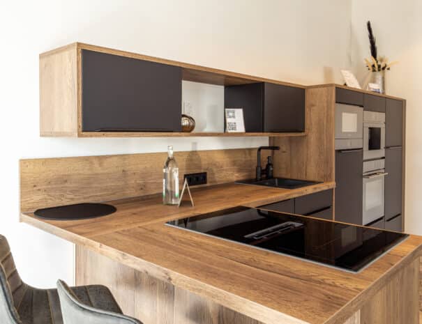Moderne Einbauküche mit Holz- und Schwarzelementen im ELBE.6 Apartment I in Wittenberge.
