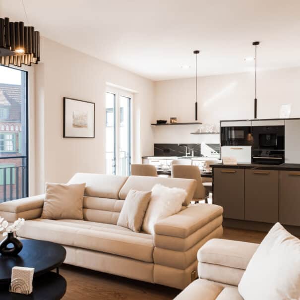 Heller Wohnbereich im ELBE.6 Apartment III mit beigen Sofas, Designküche und stilvoller Beleuchtung.