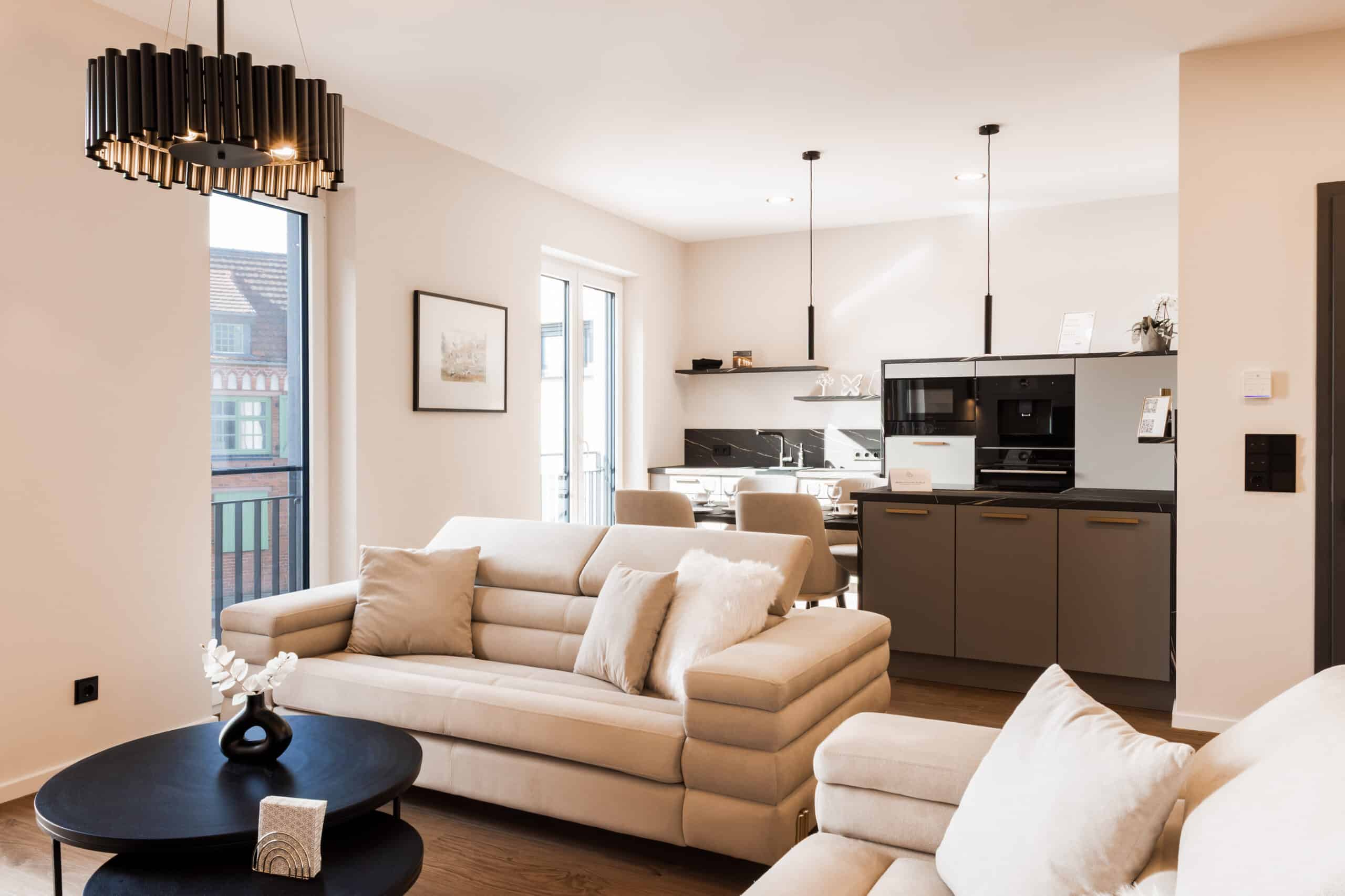 Heller Wohnbereich im ELBE.6 Apartment III mit beigen Sofas, Designküche und stilvoller Beleuchtung.