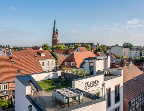 Luftaufnahme der ELBE.6 Apartments in Wittenberge mit Dachterrasse und Blick auf die Stadtkirche.