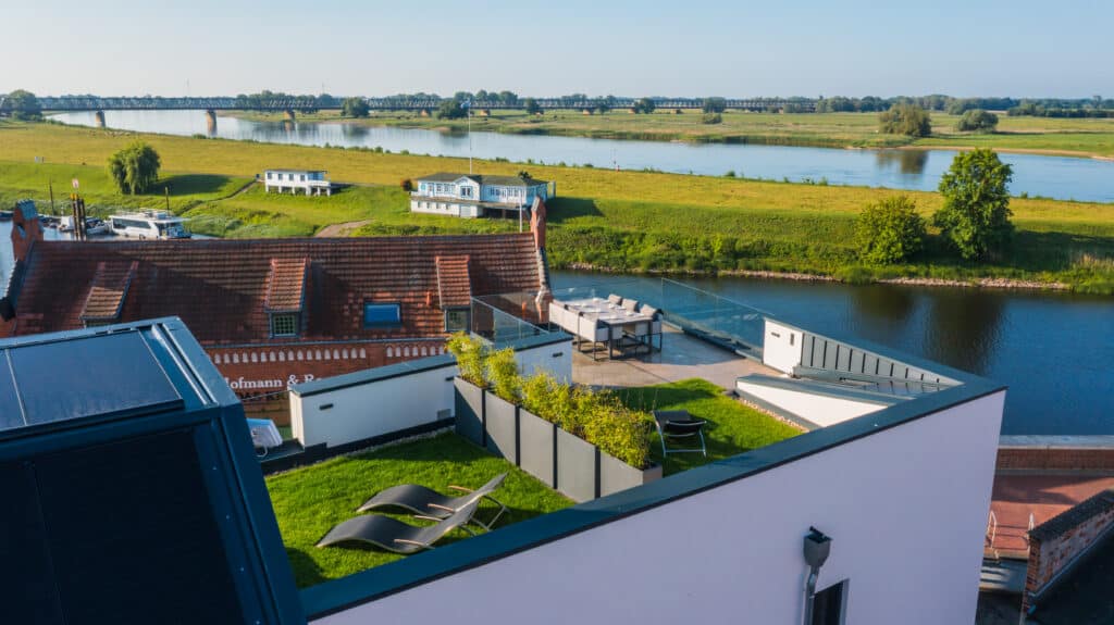 Luftaufnahme der ELBE.6 Apartments mit Dachterrasse, Sonnenliegen und Panoramablick über die Elbe und die Elbwiesen.