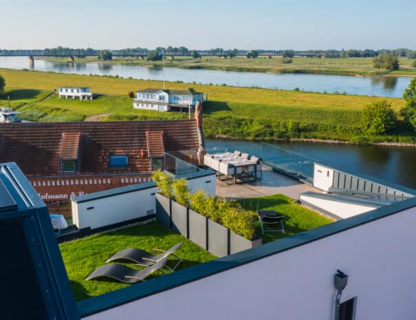 Luftaufnahme der ELBE.6 Apartments mit Dachterrasse, Sonnenliegen und Panoramablick über die Elbe und die Elbwiesen.